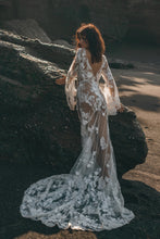 Load image into Gallery viewer, Bohemian bride in hippie wedding dress leaning against rock on beach.