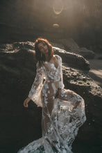 Load image into Gallery viewer, Boho bride posing against rock in low cut open back lace wedding dress.
