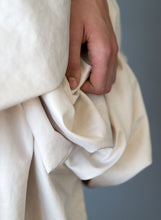 Load image into Gallery viewer, Fabric detail shot of hand, short draped wedding dress available in Vancouver shop.
