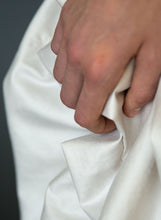 Load image into Gallery viewer, Detail of fabric and hand of silk draped Grecian wedding dress.