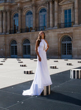 Load image into Gallery viewer, Model standing on platform, in fitted high neck wedding dress in Paris.