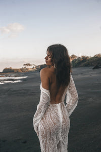 Vancouver bride shrugging shoulder of beaded fitted low back wedding dress on beach.