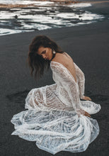 Load image into Gallery viewer, Model sitting on beach, hands in sand, showing the low back detail of lace bridal gown.
