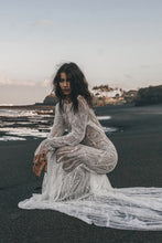 Load image into Gallery viewer, Model posing on beach with train of beaded wedding dress with long sleeve trailing behind her.