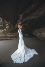 Load image into Gallery viewer, Bride in cave with arms up wearing a boho fit-and-flare lace wedding dress.
