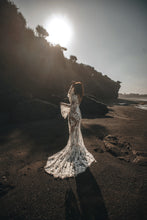 Load image into Gallery viewer, Bride on beach with hands in air showing boho sleeves and long train of wedding dress.
