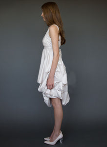 Model, full length, side view, wearing sleeveless below the knee maternity short wedding dress.