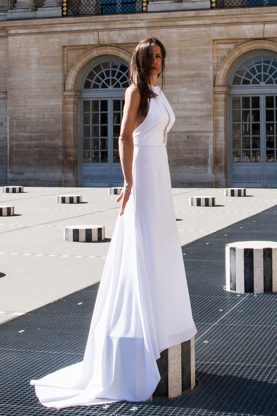Model in Paris, full length, standing on platform wearing low back wedding dress.
