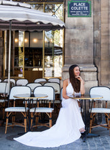 Load image into Gallery viewer, Bride in Paris sitting outside at cafe wearing halter neck wedding dress.
