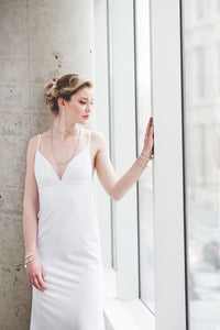 A fitted crepe wedding gown with open back and lace up straps. 