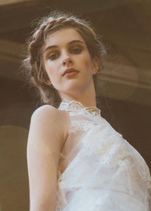 Detail shot of model wearing high neck sleeveless short lace wedding dress.