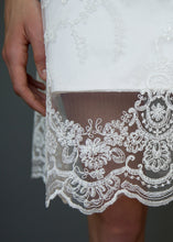 Load image into Gallery viewer, Fabric close up of hemline overlay on short skirt on lace wedding dress for Vancouver brides.
