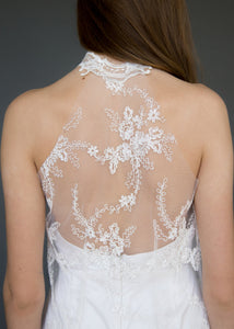Detail shot of back of model wearing lace overlay dress over short strapless wedding dress.