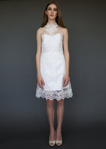 Model standing, wearing knee length strapless short wedding dress.
