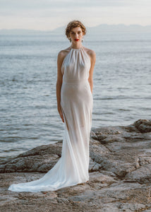 Bride standing with flowy bridal dress and halter top by custom wedding dress designer.