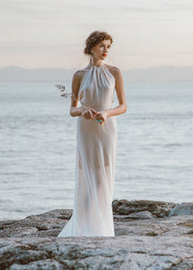 Bride standing on rock wearing halter wedding dress.