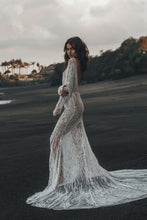 Load image into Gallery viewer, Model standing on beach with her profile showing backless feature of beaded Vancouver wedding dress.
