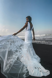 Vancouver bride holding up white lace wedding dress on beach.